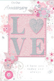 The anniversary card shown here offers a gentle celebration of lasting romance, blending soft pastel pinks, muted greys, and shimmering silver tones that would look perfectly at home on a Wood Green mantelpiece. At its centre, the word LOVE appears in raised, glitter-lined letters, the surface dusted with a fine sparkle that catches and reflects the light with every slight movement. The letter O is transformed into a softly gleaming heart, filled with textured silver that makes it the focal point of the design, much like a statement bloom in the centre of a romantic bouquet. Around this word, delicate flowers in blush and mauve shades unfurl with an almost watercolour softness, the edges of their petals gently blurred to suggest lightness and air. Their slender stems twist into graceful swirls and loops that echo the flowing shapes of vines, reminiscent of the natural, organic curves a Wood Green florist might create when arranging an anniversary gift for delivery to nearby homes and cafés. Subtle details-floating petals, tiny butterflies, and airy curls-add a sense of motion and playfulness, as if a spring breeze from Alexandra Park had set the flowers gently in motion. Above and below the central motif, the words On Our Anniversary and I love you today and always are written in a refined, flowing script, their lines echoing the curves of the floral artwork. The composition feels intimate and heartfelt, as soft as a shared whisper at the end of a long day, making this card an ideal keepsake for honouring a couple's shared journey and the quiet rituals of love that unfold year after year in Wood Green.